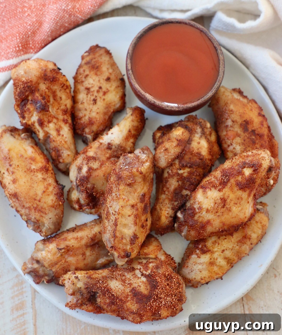 Perfectly cooked sous vide chicken wings ready to be sauced, presented on a plate with a side of buffalo sauce.