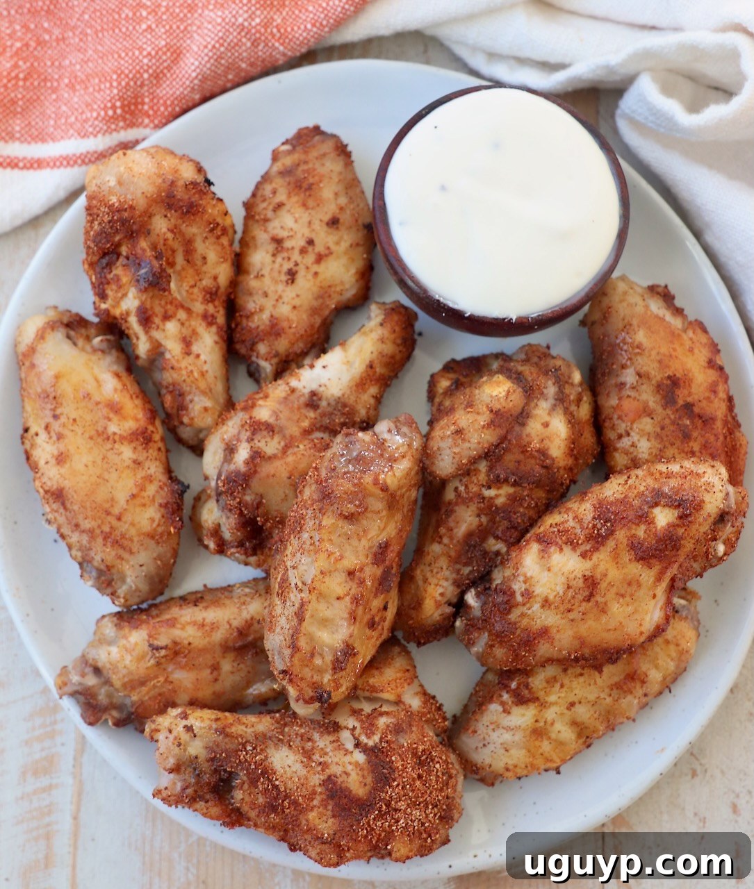 A plate of perfectly cooked sous vide chicken wings, accompanied by a small bowl of creamy blue cheese dressing.