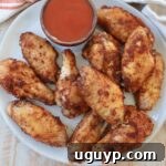 cooked chicken wings on plate with small bowl of buffalo sauce