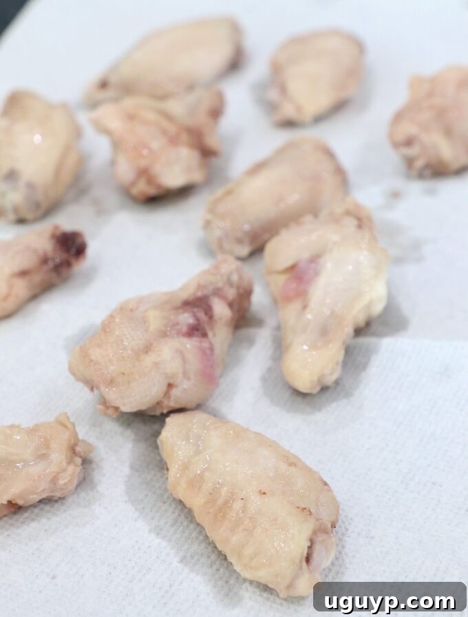 Cooked sous vide chicken wings resting on paper towels, ready to be dried for the crisping stage.