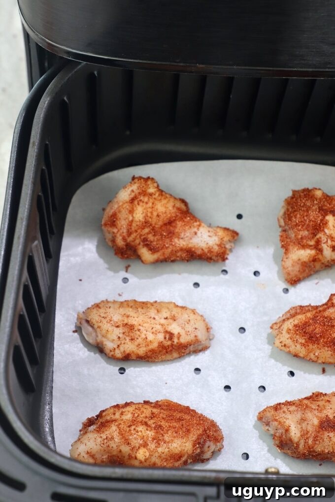 Seasoned chicken wings cooking in an air fryer basket, achieving a perfect golden crisp.