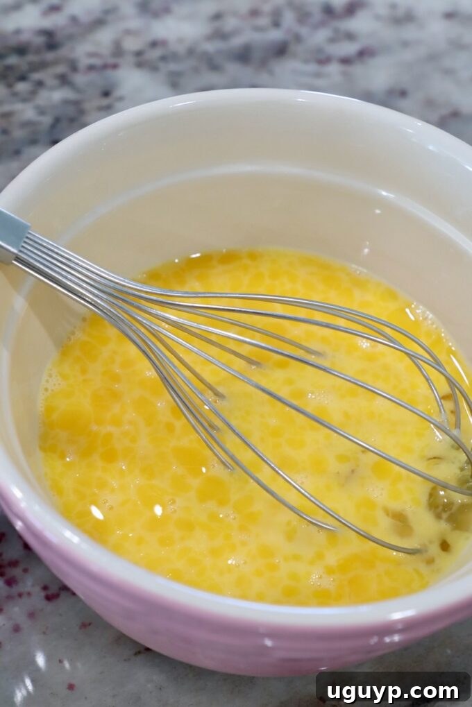 whisked eggs in mixing bowl with large whisk