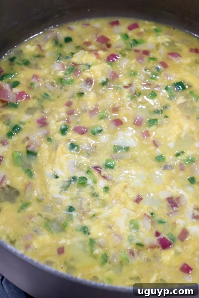 whisked eggs in skillet with jalapenos and onions