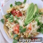migas on plate with fork, topped with sliced avocado
