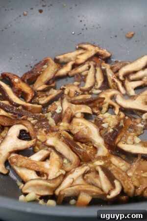 Cooked shiitake mushrooms in a wok with garlic and ginger.