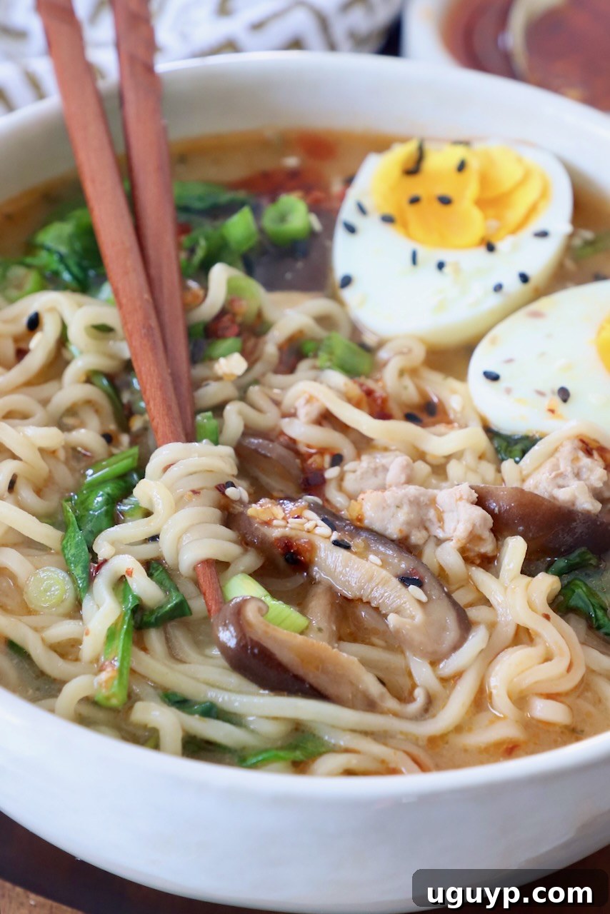 A close-up of a beautifully plated bowl of Miso Ramen, featuring noodles, pork, an Ajitama egg, and garnished with fresh green onions and seaweed, with chopsticks poised for enjoyment.