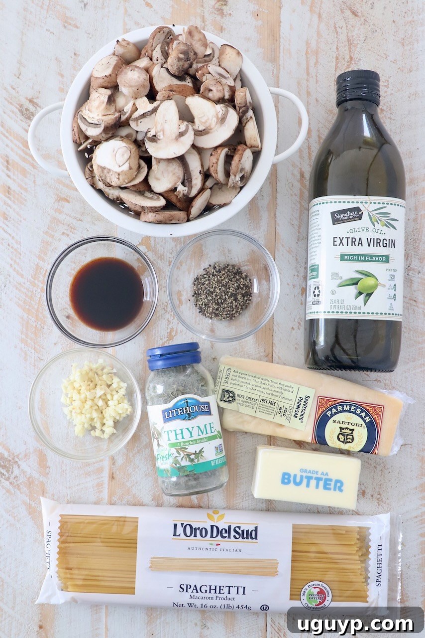 A selection of fresh ingredients for mushroom pasta laid out on a white wooden board, including spaghetti, mushrooms, garlic, and herbs.
