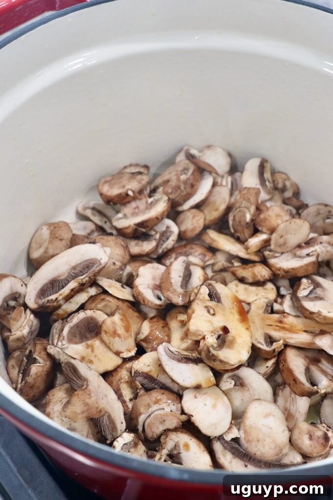 Sliced mushrooms being sautéed in a pot with soy sauce, developing rich color.