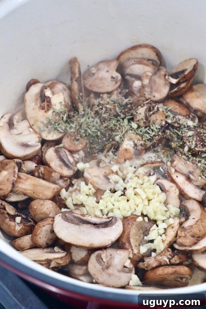Minced garlic, dried thyme, and black pepper added to sautéed mushrooms in a pot, releasing their aromas.