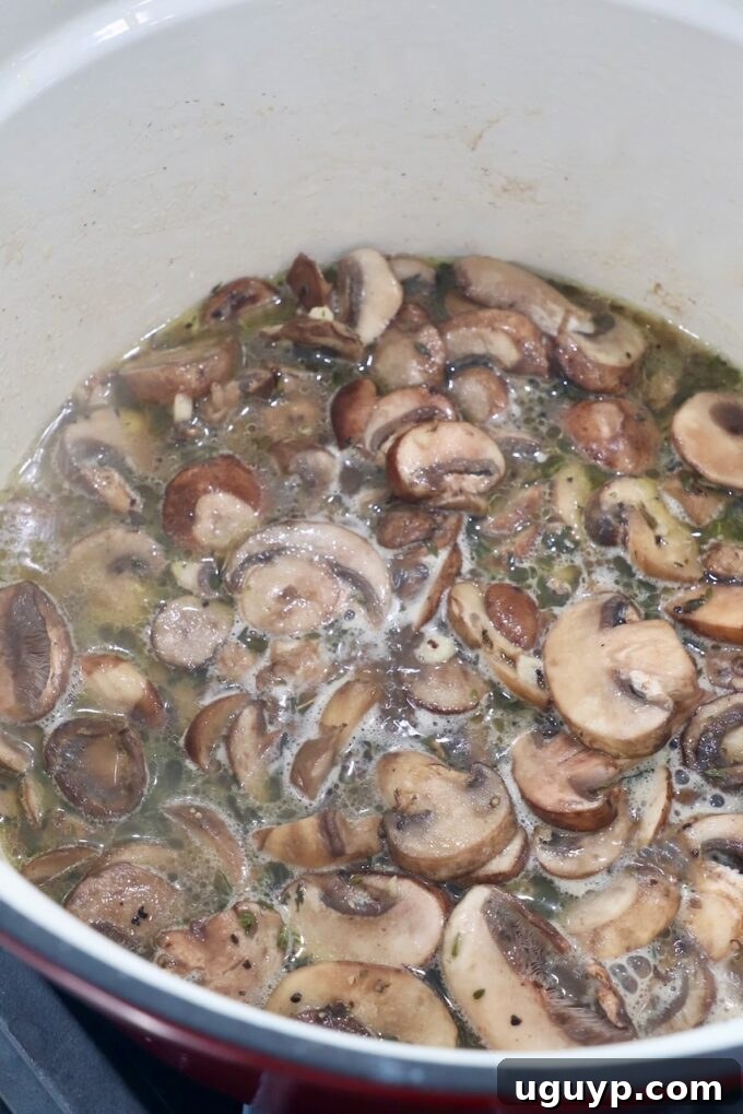 Sautéed mushrooms simmering in a pot with reserved pasta water, creating a light sauce.