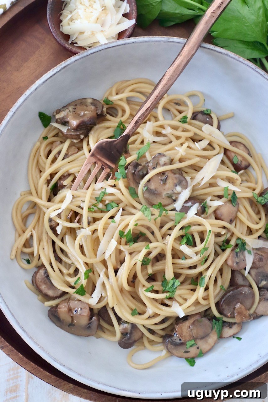 Another perspective of the delicious mushroom pasta in a bowl with a fork, garnished with fresh parsley.