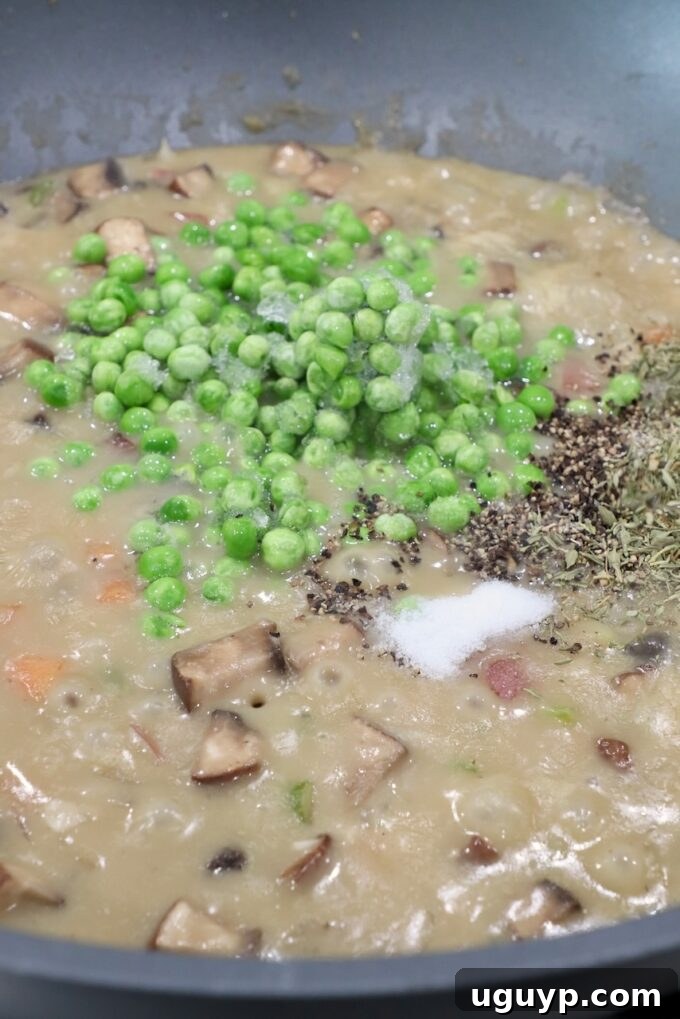 frozen peas and spices in pan of vegetable pot pie filling