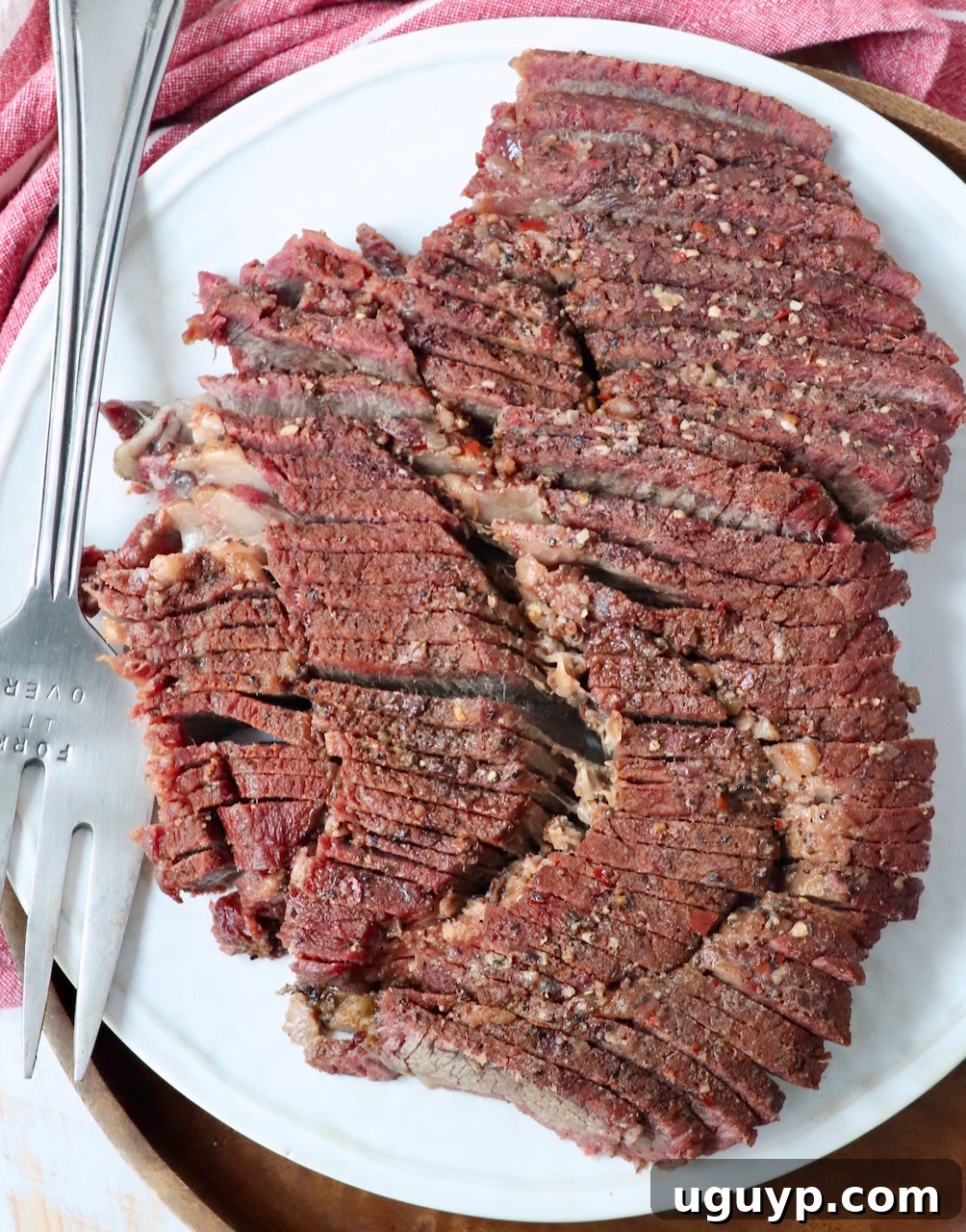 Sliced smoked chuck roast on a plate with a serving fork, ready to be enjoyed.