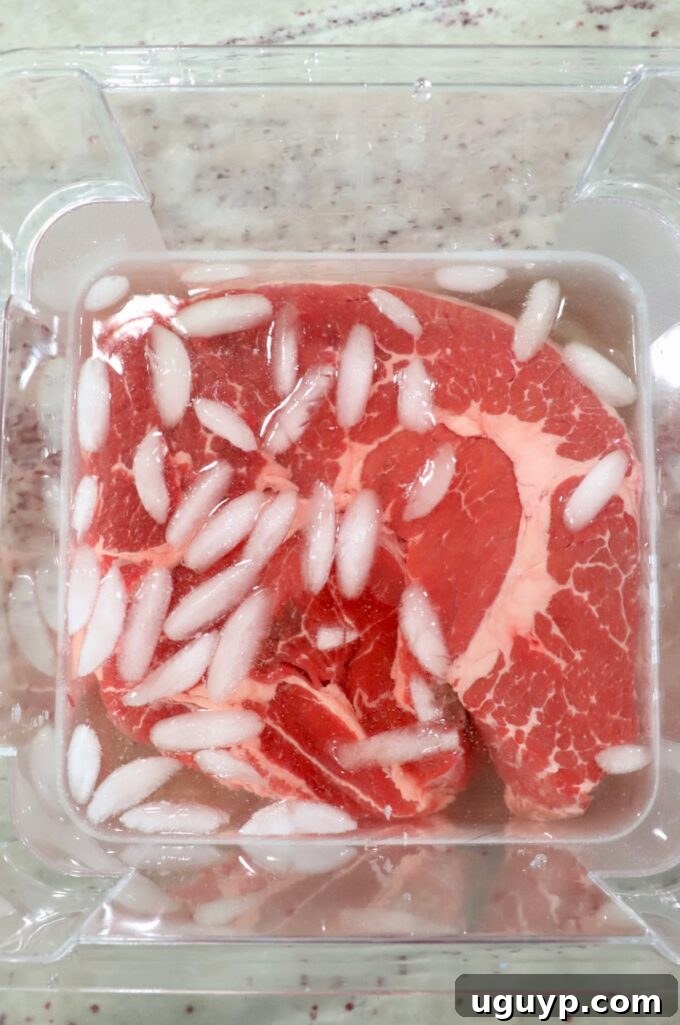 Chuck roast soaking in a flavorful brine with ice cubes in a plastic tub, preparing for smoking.