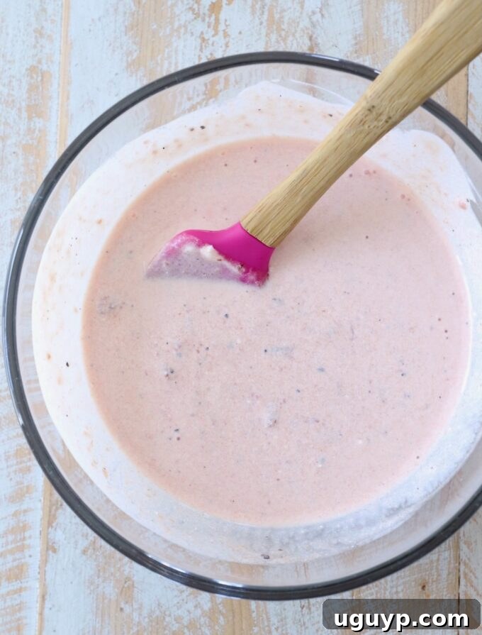 Sour cream and salsa combined in a glass bowl, being mixed with a spatula to create the taco salad dressing.