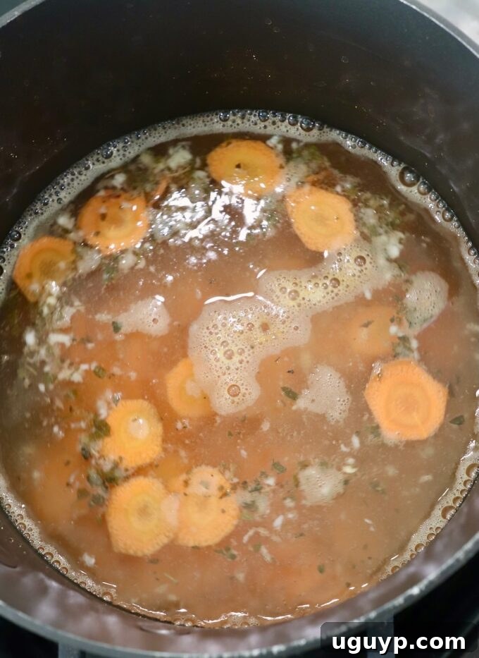 Thinly sliced carrots submerged in the flavorful pickling liquid within a pot on the stove, gently cooking to achieve the perfect crisp-tender texture.