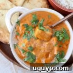 Prepared Indian butter paneer in a white bowl with a copper spoon, showcasing the rich texture of the curry.