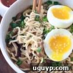 A delicious bowl of cooked ramen noodles with chopsticks and a soft-boiled egg, ready to be enjoyed.