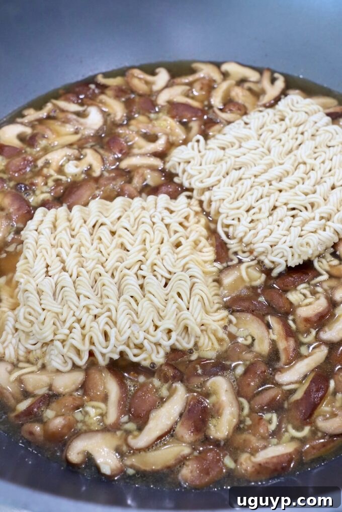 Ramen noodles simmering in the flavorful broth alongside sautéed mushrooms in a large pot on the stove, absorbing all the delicious spices and aromatics.