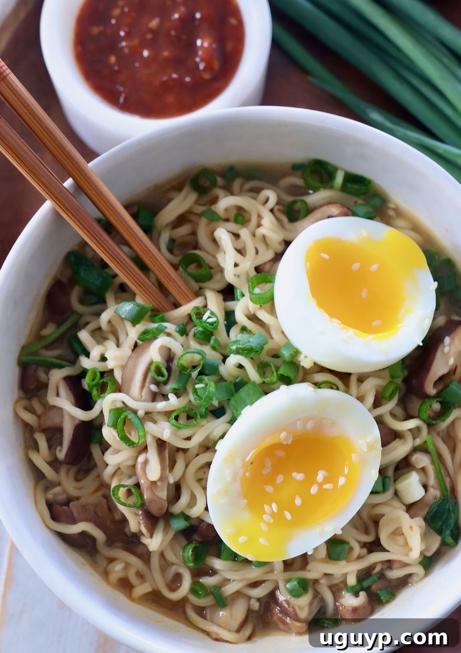 Close-up of a prepared ramen noodle soup in a bowl with a soft-boiled egg, ready to be enjoyed with chopsticks.