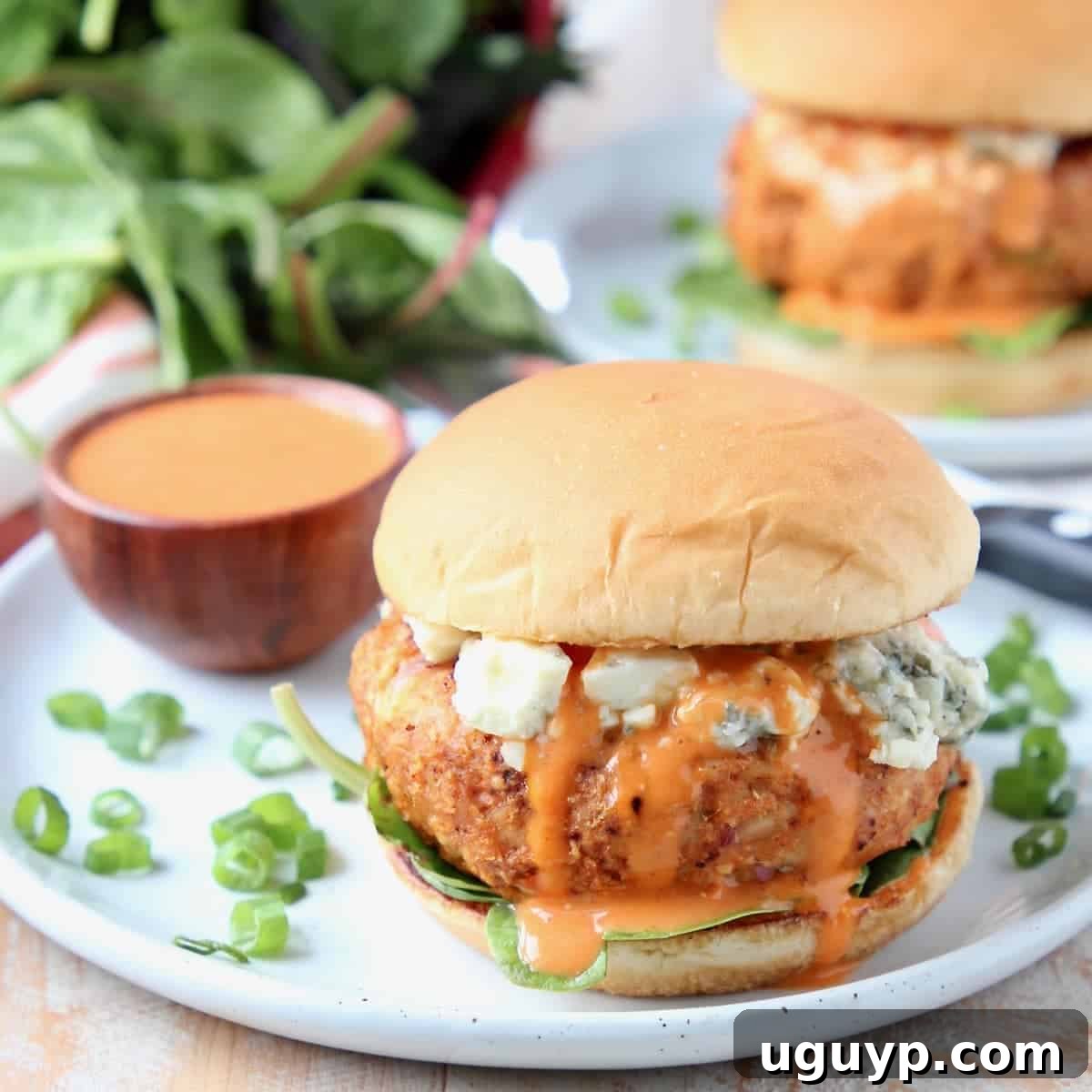 A juicy buffalo chicken burger on a bun, topped with blue cheese crumbles and drizzled with buffalo wing sauce.