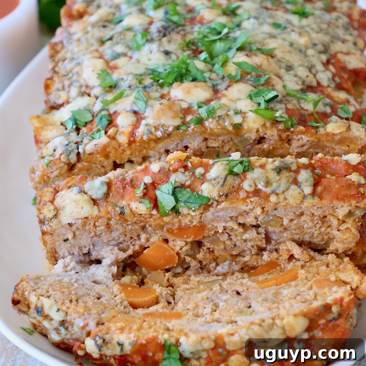 A thick slice of Buffalo Chicken Meatloaf, revealing its juicy interior, served on a plate.