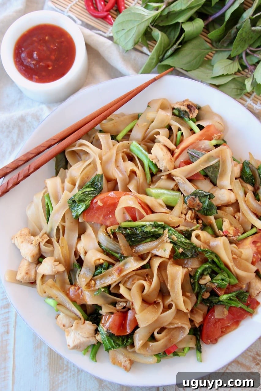 Overhead shot of Drunken Noodles on white plate with brown chopsticks on the side