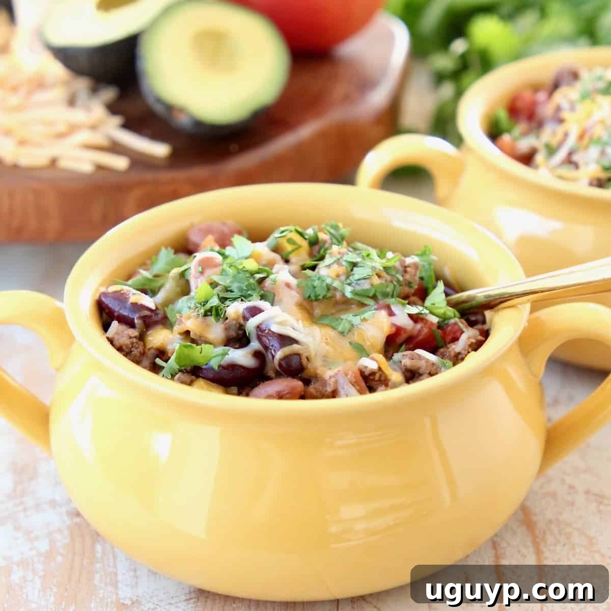 Crockpot Taco Soup in yellow crock with gold spoon, topped with cheddar cheese and fresh cilantro