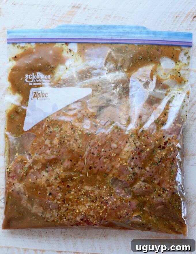 Skirt steak submerged in marinade inside a large zipper bag