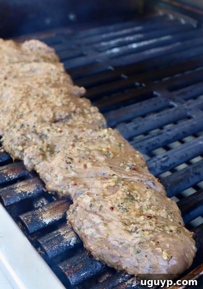 Marinated skirt steak being placed onto a hot grill