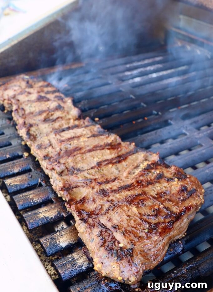 Skirt steak cooking on a hot grill, showing grill marks