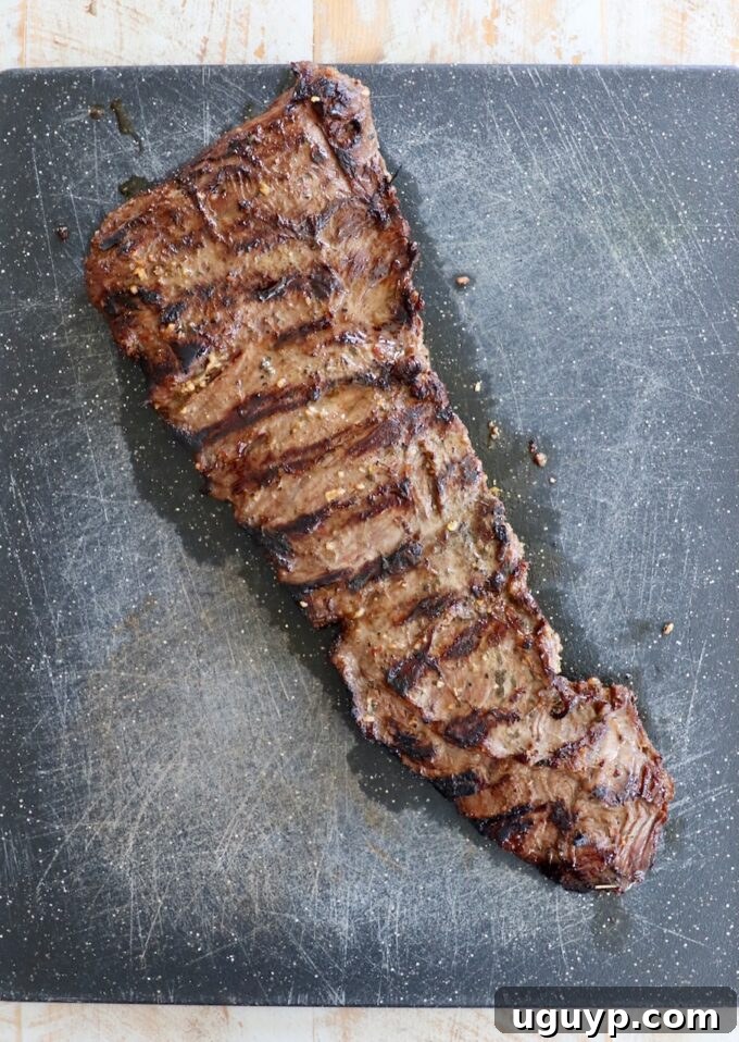 Grilled skirt steak resting on a wooden cutting board