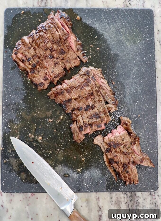 Sliced grilled skirt steak on a cutting board next to a large knife