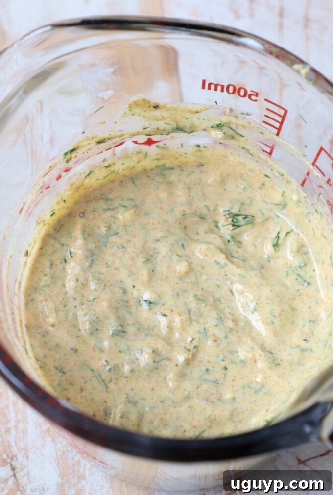 creamy curry dill Greek yogurt salad dressing in a glass bowl, ready to be mixed with pasta