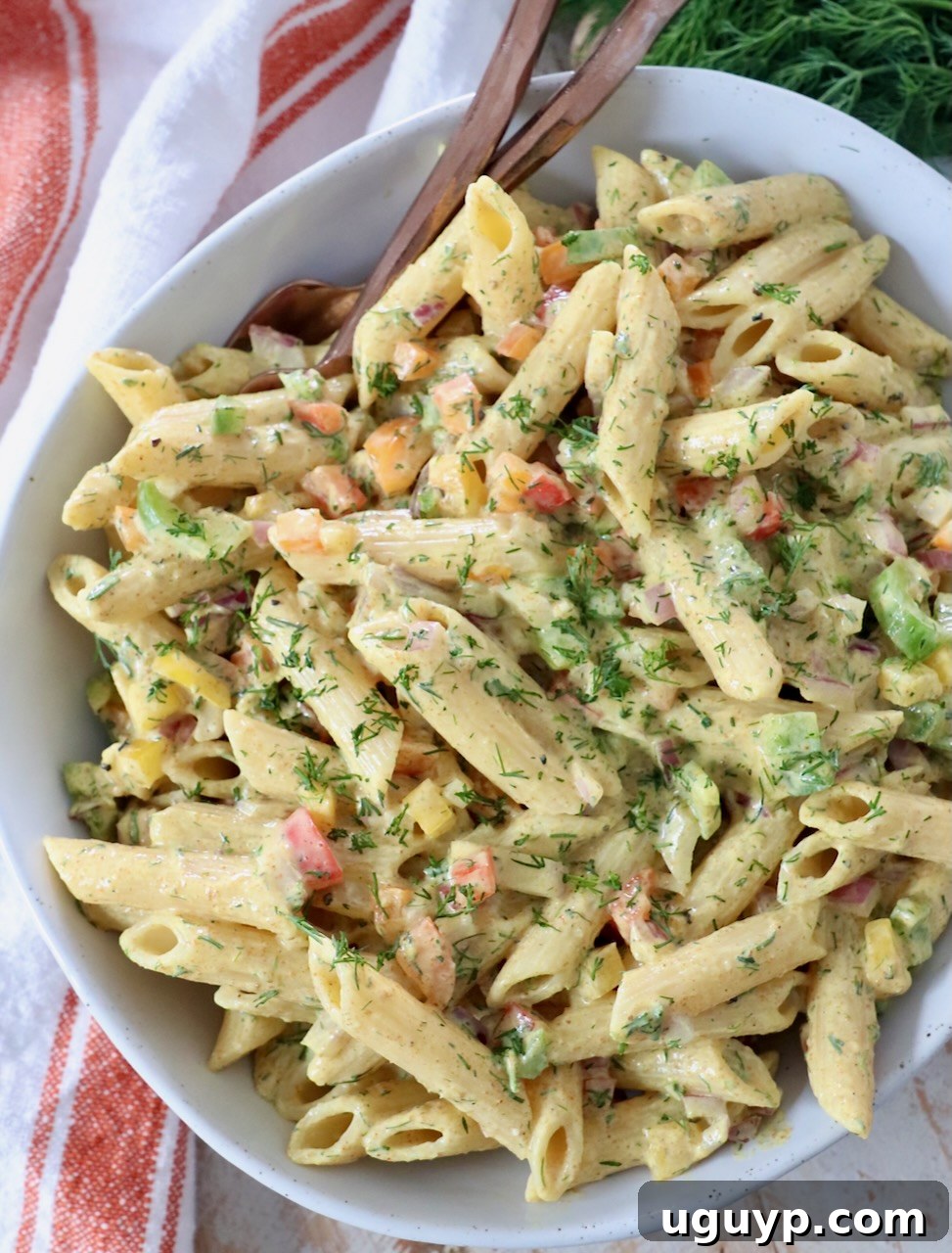 creamy curry pasta salad in a white bowl with two forks, ready to be served