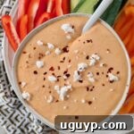 Roasted red pepper feta dip in a bowl topped with feta cheese crumbles and red pepper flakes