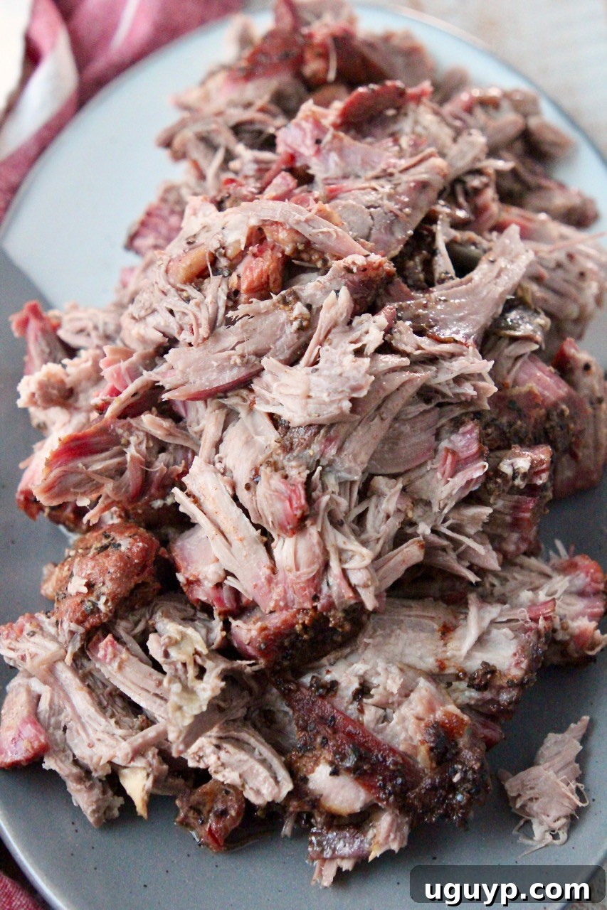 Tender, juicy smoked pulled pork piled high on a plate, ready to be served.