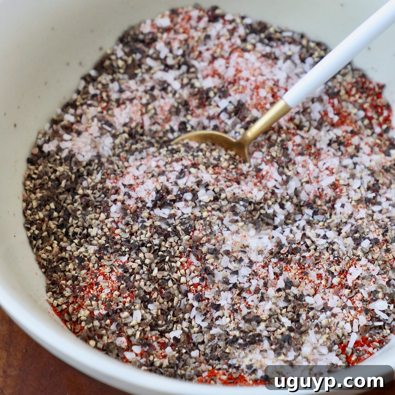 All the ingredients for the pulled pork rub mixed together in a bowl with a spoon.