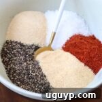 Spices in a bowl with a gold and white spoon, showcasing the blended pulled pork rub.