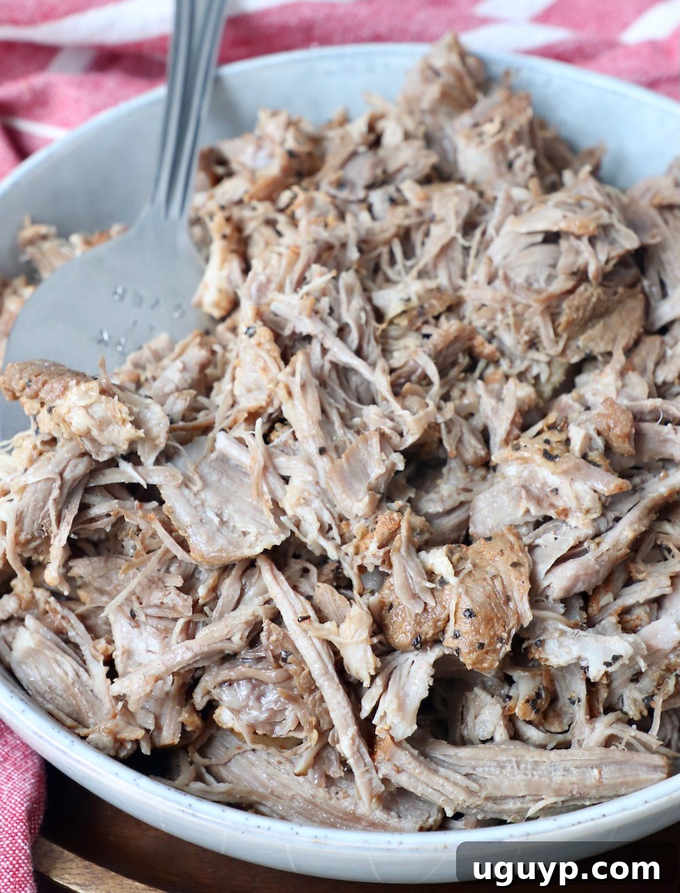 Pulled pork in a bowl with a large serving fork, ready to be enjoyed