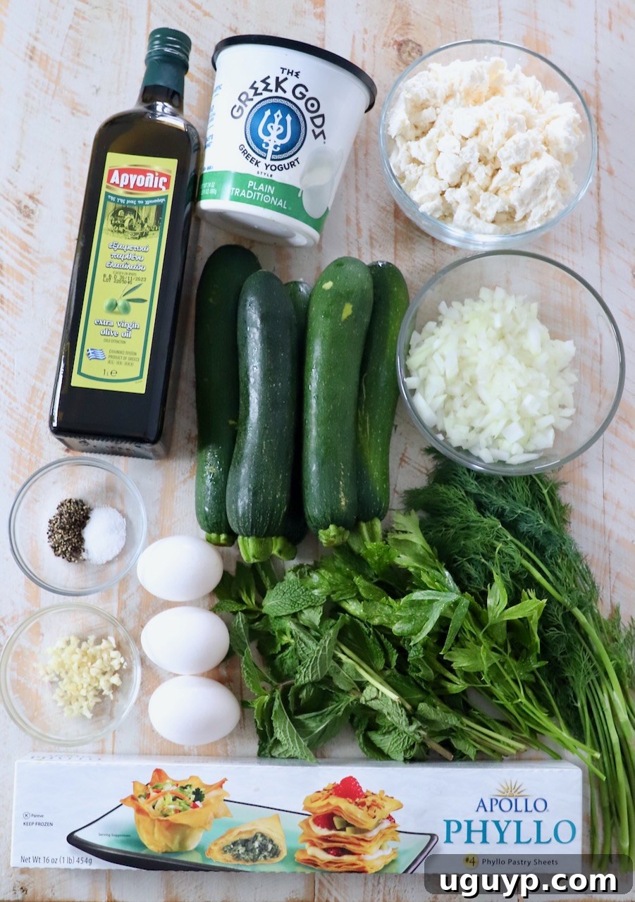 Fresh ingredients for Greek zucchini pie laid out on a white wooden board, including zucchini, feta, herbs, and olive oil.