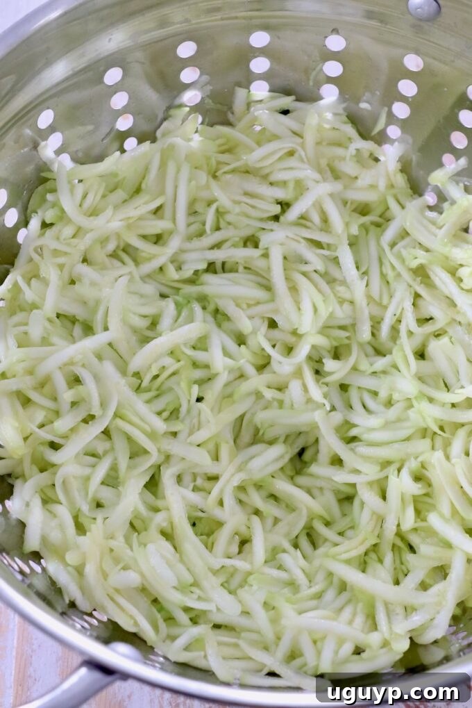 Grated zucchini in a colander, salted and left to drain excess moisture, an essential step for a non-soggy pie.