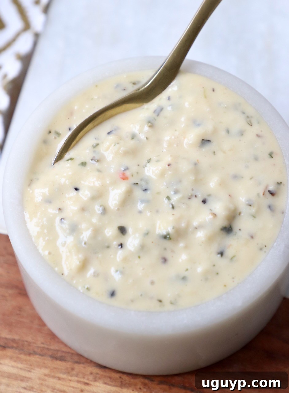 Creamy Garlic Parmesan Sauce in a small bowl with a gold spoon, ready to be served.