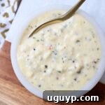 Garlic Parmesan Sauce in a bowl with a spoon, garnished with herbs.