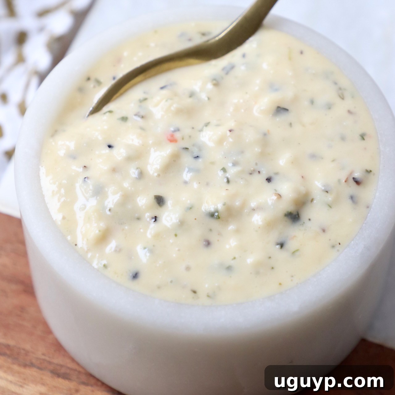 Small bowl of creamy garlic parmesan sauce with a spoon, ready for use.