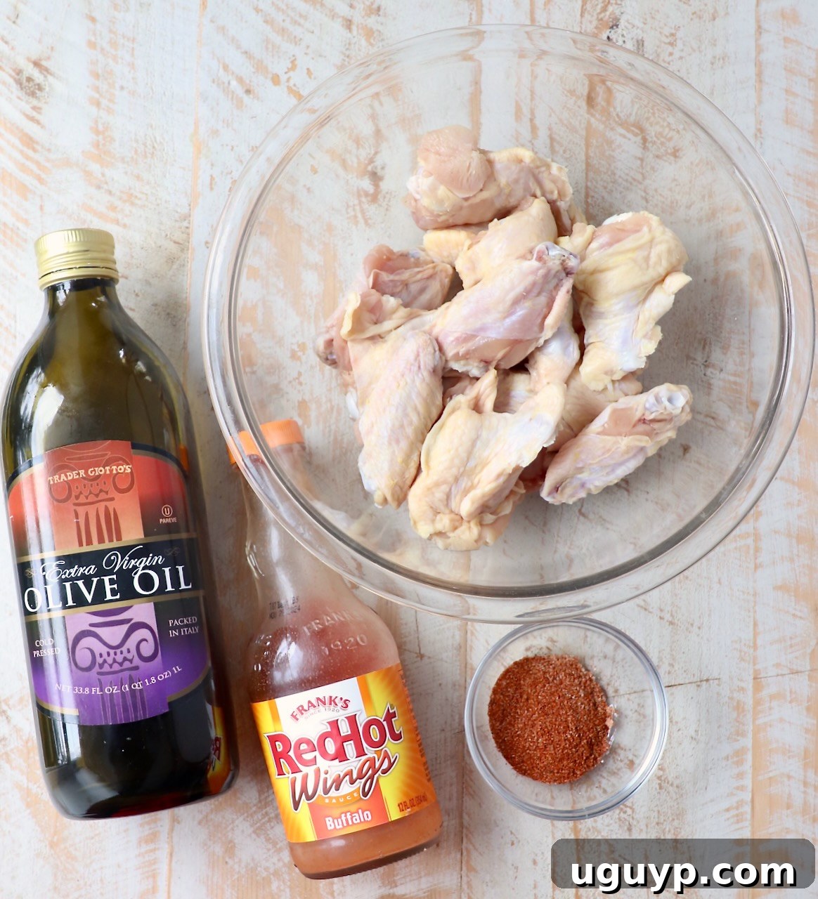 A beautiful flat lay of all the fresh ingredients for grilled chicken wings laid out on a rustic white wooden board, showcasing their vibrant colors and textures.
