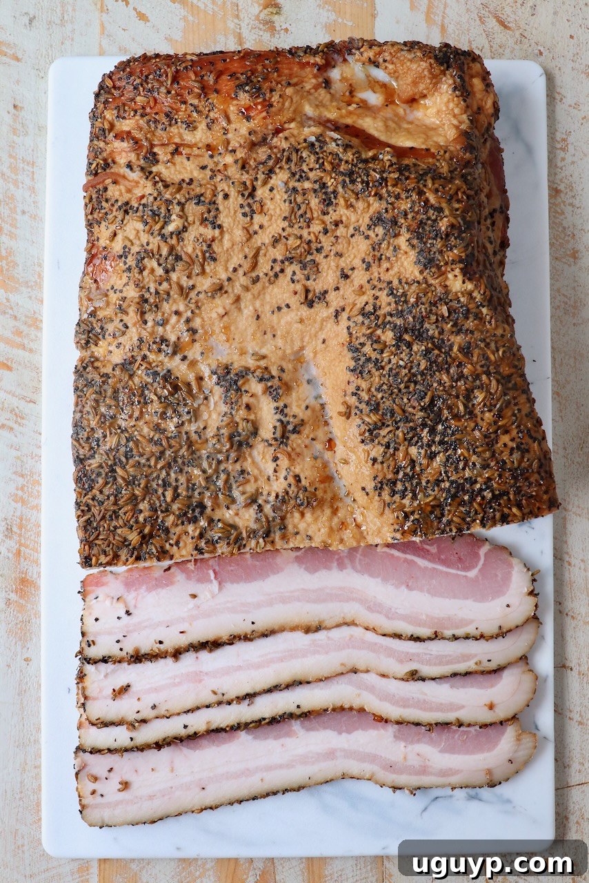Homemade bacon, partly sliced, resting on a rustic cutting board