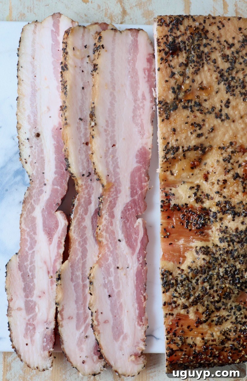 Thick, perfectly sliced bacon from a smoked pork belly, displayed on a rustic cutting board.