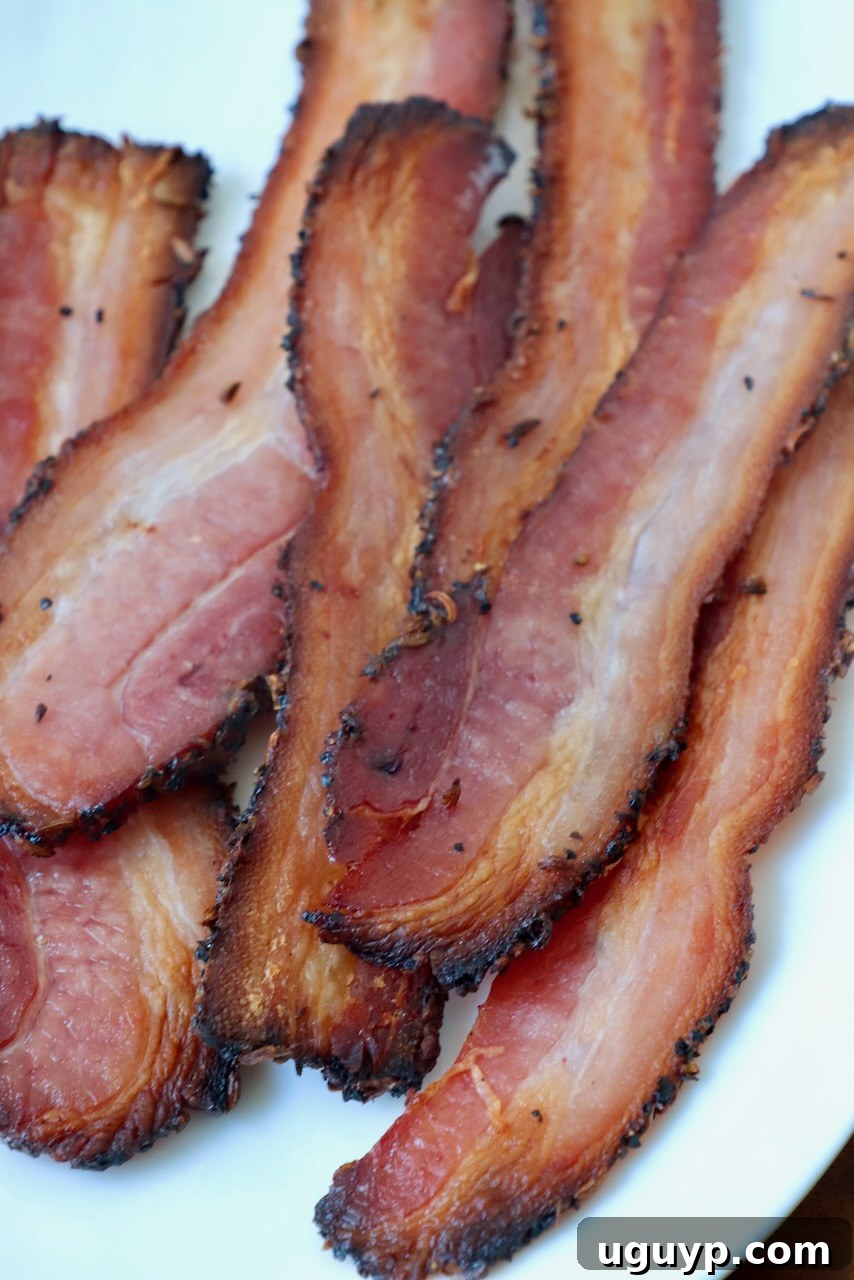 An inviting plate of perfectly cooked, sliced homemade bacon, ready for serving.