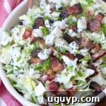 chopped salad in bowl topped with blue cheese and bacon